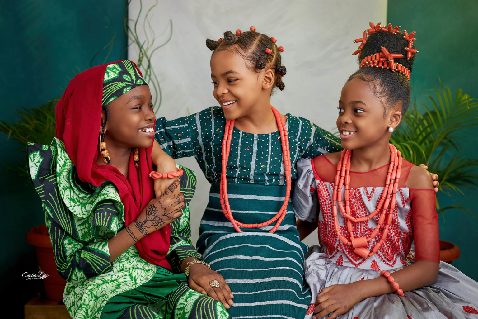 Three female children smiling happily and in traditional attire