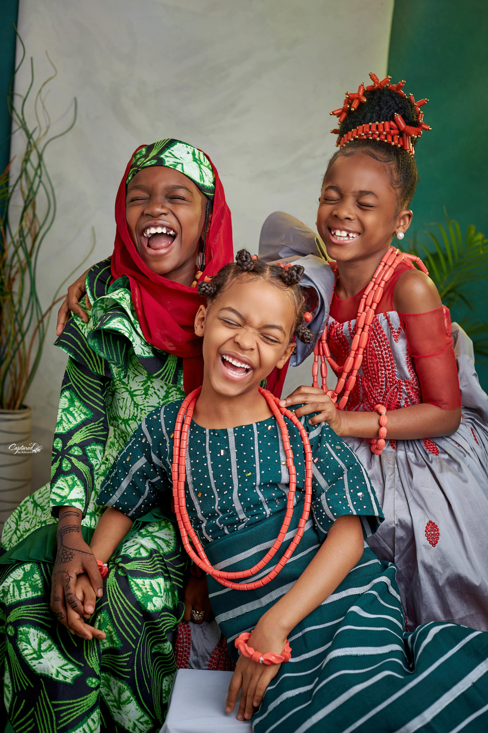 Three female children smiling happily and in traditional attire